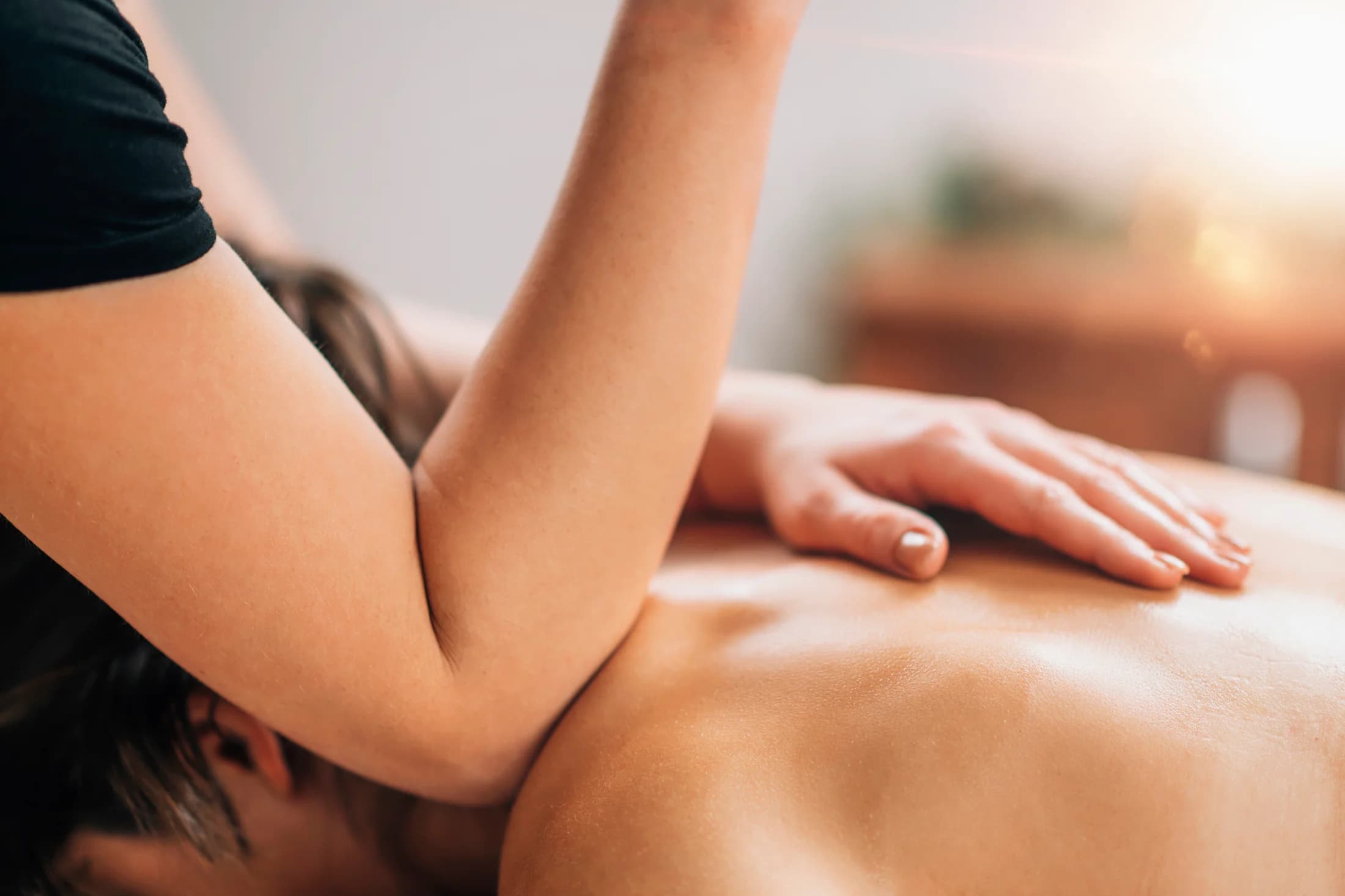Deep tissue massage using forearm pressure on the client's upper back