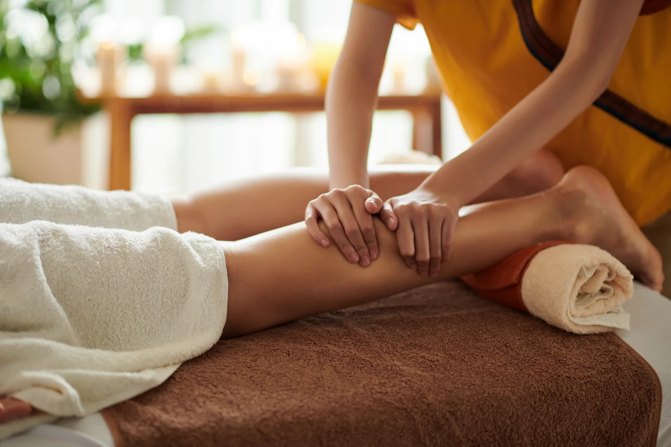 Therapist massaging a client's calf muscle on a treatment table
